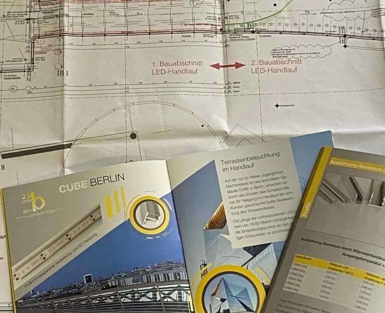 Verschiedene Architekturpläne und Beleuchtungsbroschüren auf einer Fläche ausgebreitet.